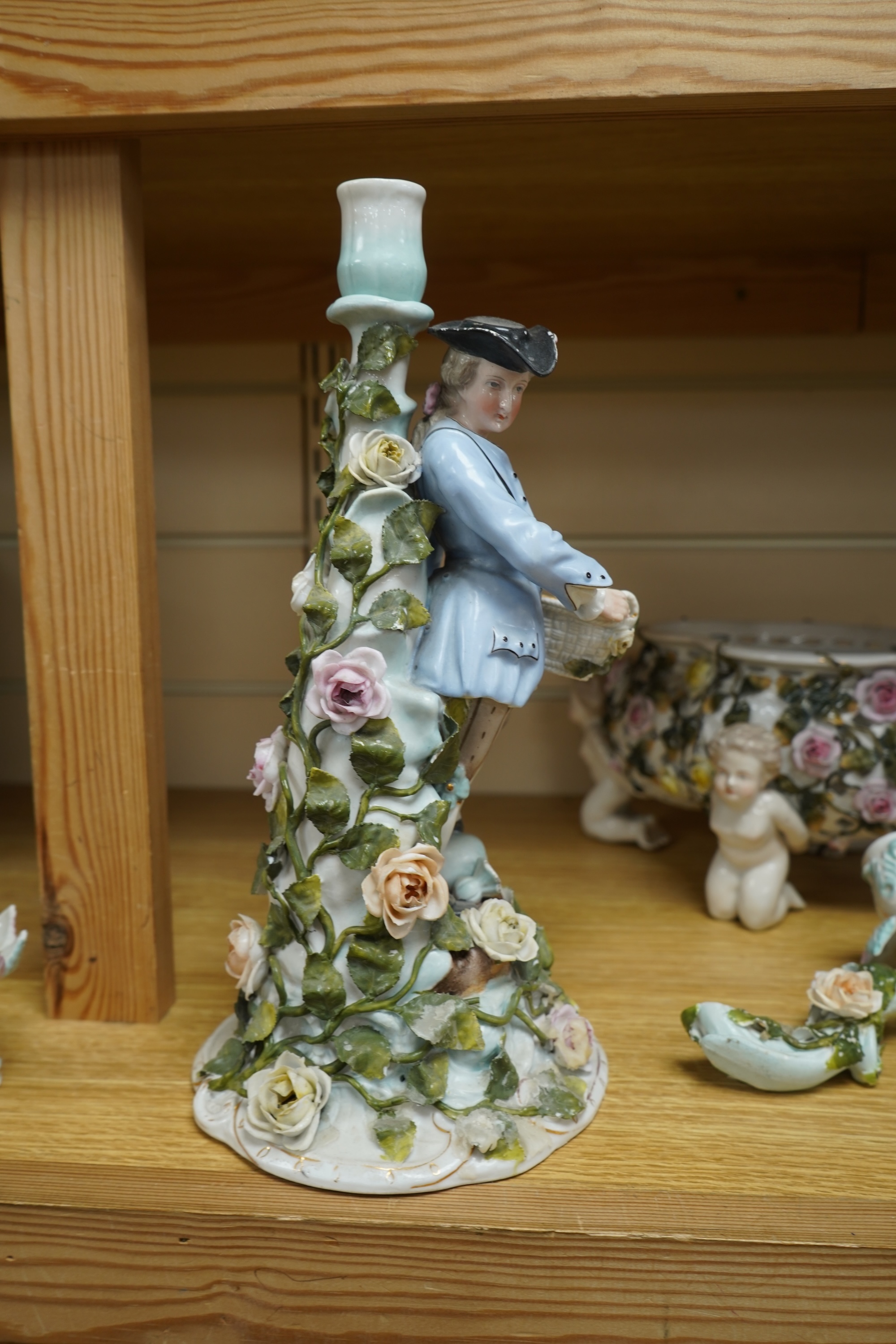 A German flower encrusted porcelain figural candelabrum, 30cm high, a cherub jardiniere and a cherub vase, all encrusted